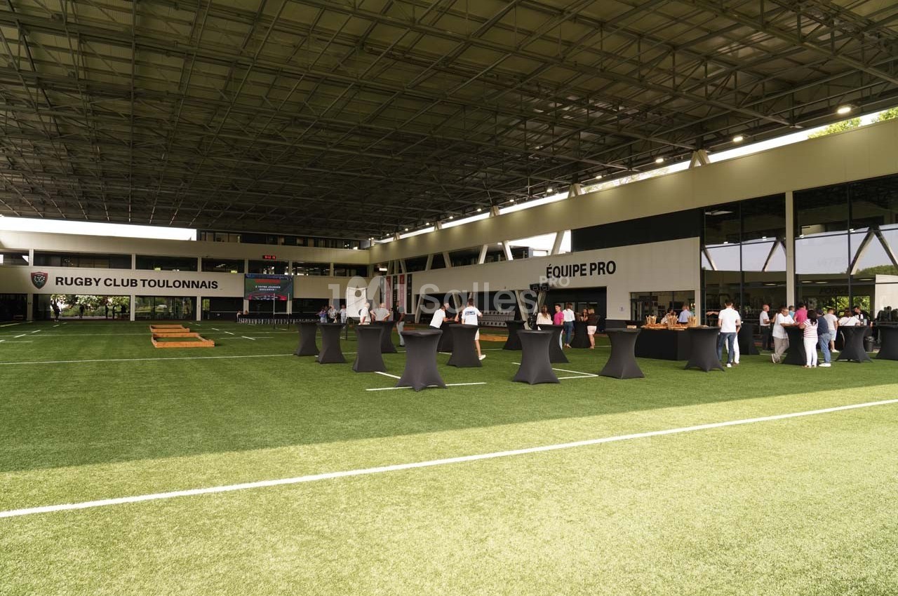 Terrains couverts avec des tables hautes et des groupes de personnes dans un centre d'entraînement sportif.