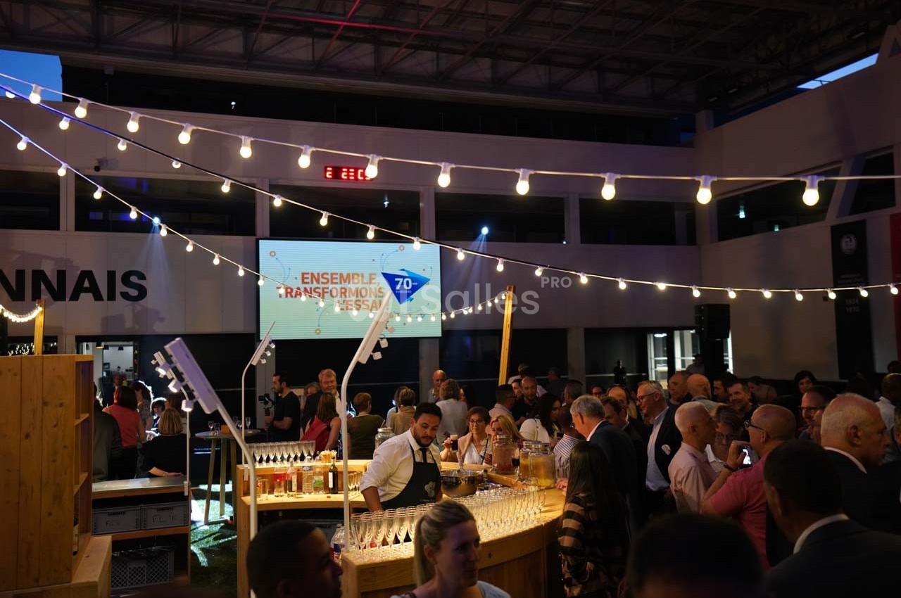Un groupe de personnes rassemblées dans un espace intérieur éclairé, autour d'un bar en bois, lors d'un événement festif.