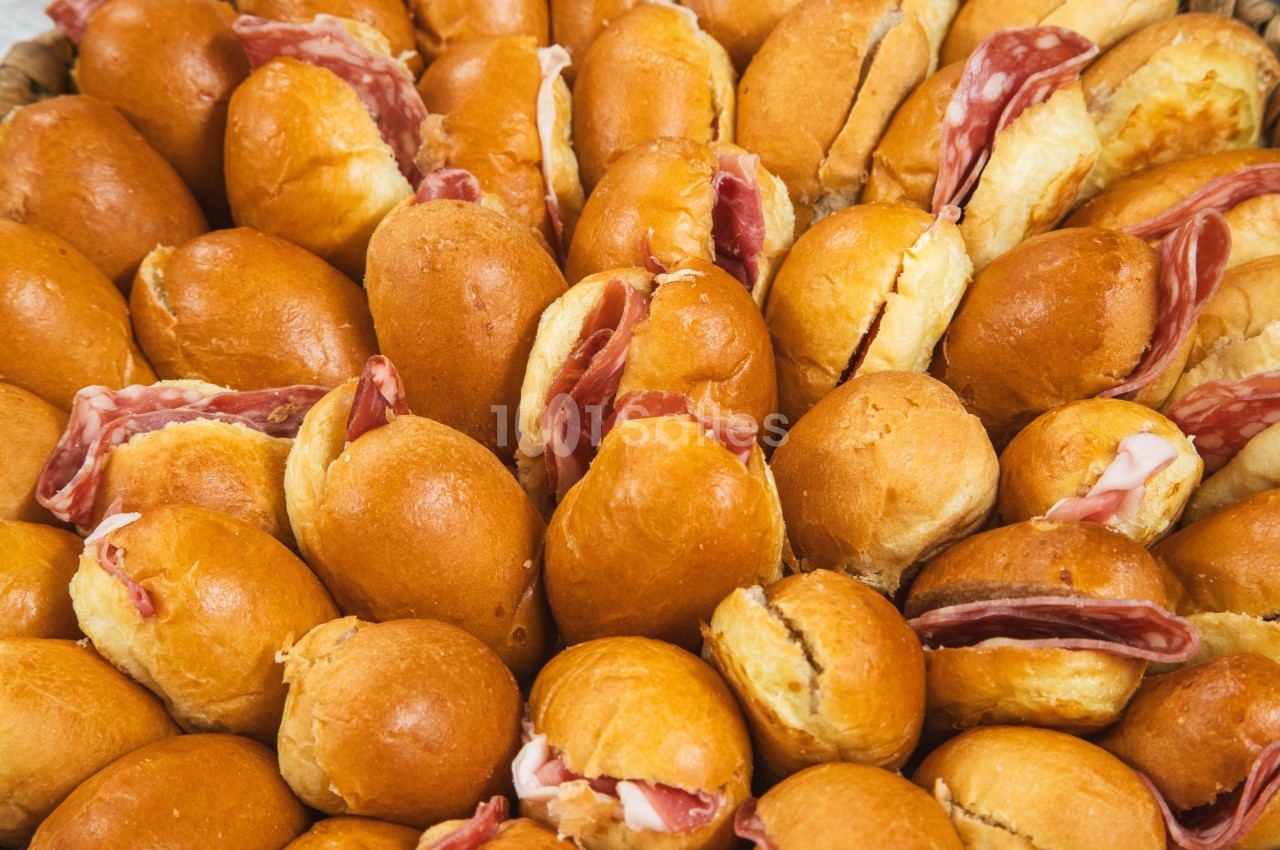 Assortiment de petits pains briochés garnis de tranches de charcuterie.