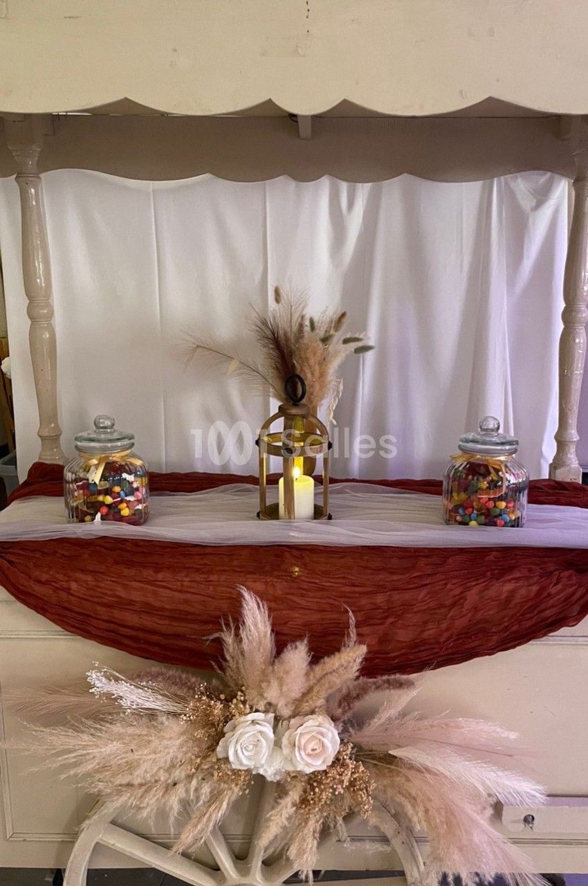 Chariot décoratif avec pots de bonbons, lanterne allumée et ornements de fleurs et d'herbes séchées.