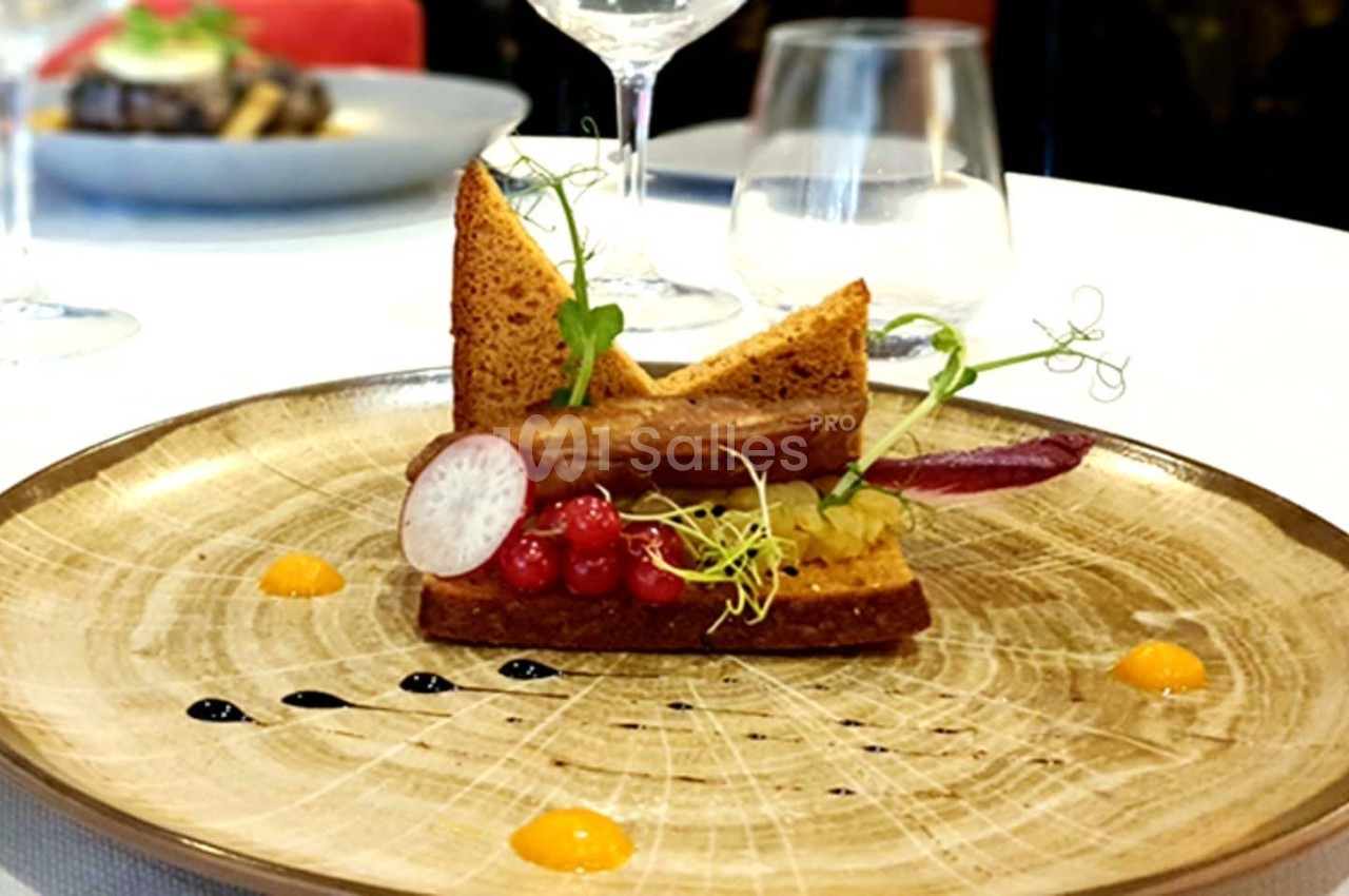 Assiette gastronomique composée de pain grillé, légumes, groseilles et sauces colorées, servie sur une table élégante.