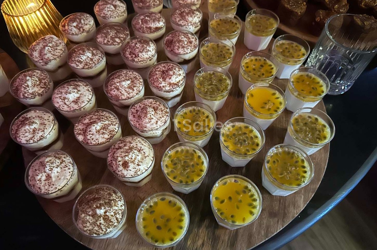 Plateau de verrines sucrées, dont certaines au chocolat et d'autres au fruit de la passion, disposées sur une table en bois.
