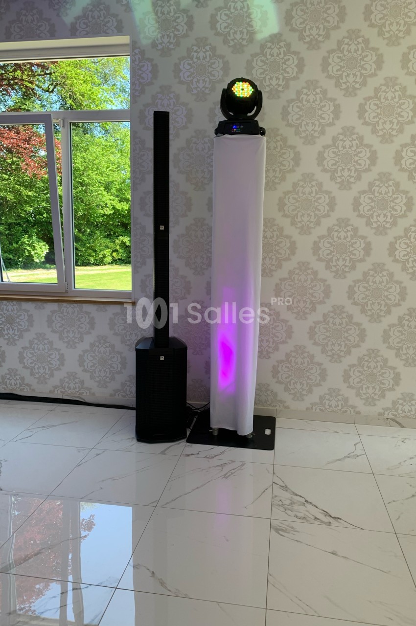 Système de sonorisation et éclairage avec colonne lumineuse et projecteur LED, installé dans une pièce lumineuse.