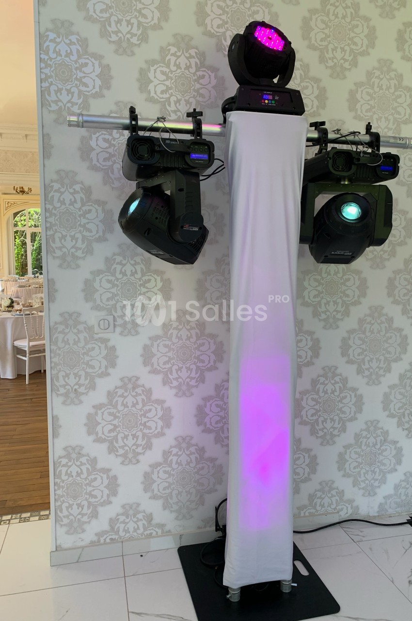 Équipement d'éclairage de scène avec projecteurs et spots montés sur une structure métallique, dans une salle décorée.