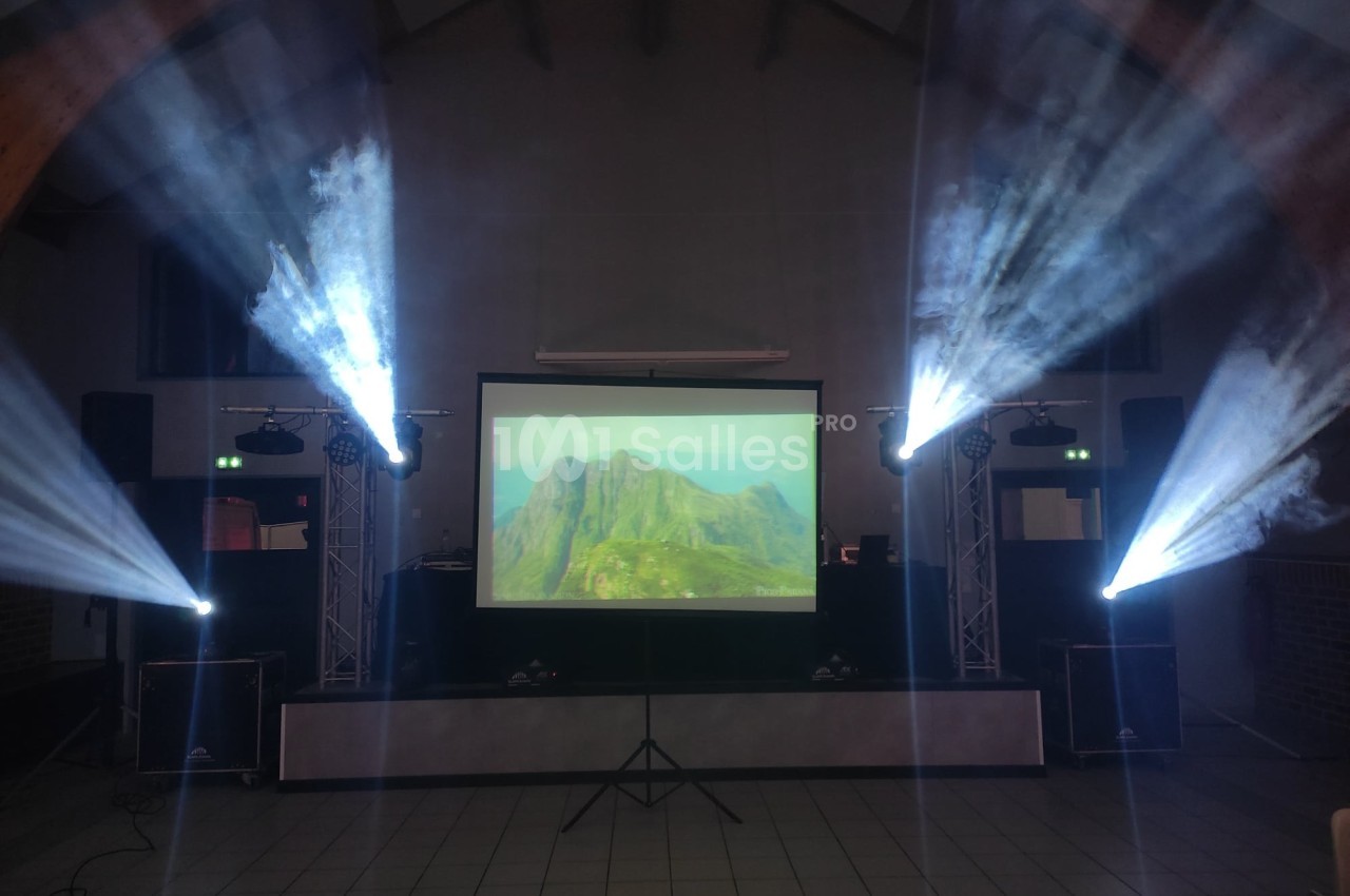 Écran de projection affichant un paysage montagneux, entouré de jeux de lumière dans une salle sombre.