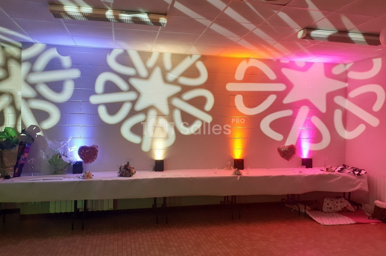 Décoration lumineuse projetant des motifs étoilés colorés sur un mur blanc, avec une table dressée en dessous.