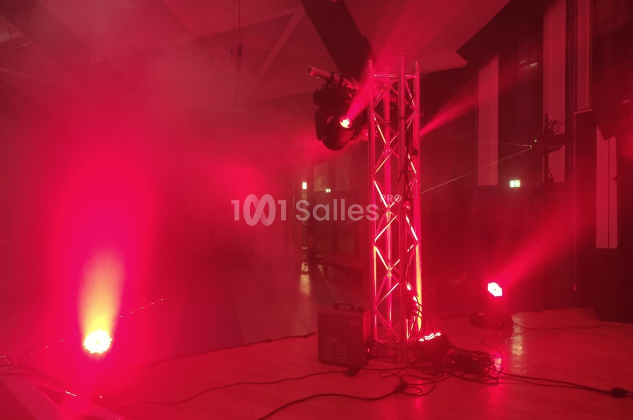 Éclairage de scène rouge avec projecteurs et fumée dans une salle intérieure.