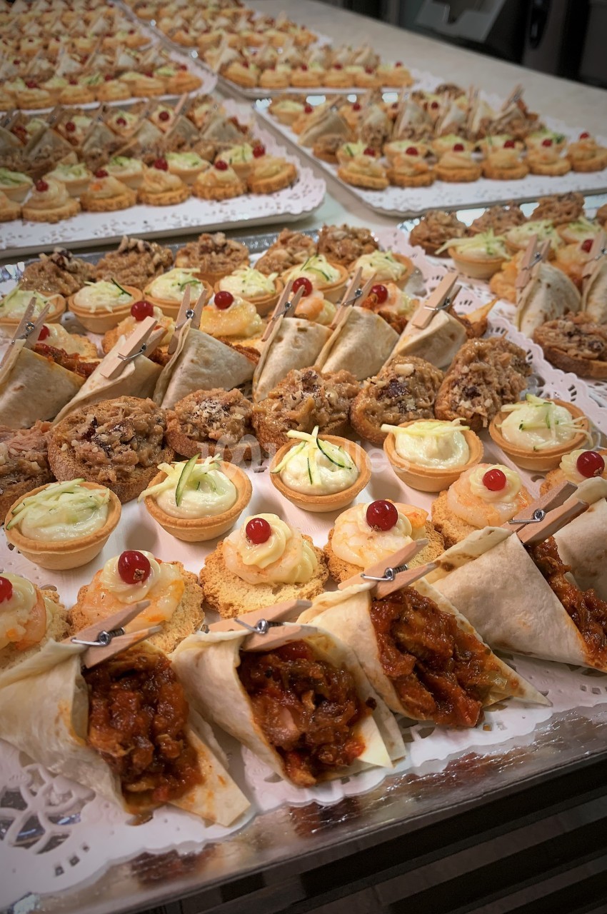 Plateau de bouchées variées comprenant wraps, tartelettes salées, biscuits et amuse-bouches décorés.