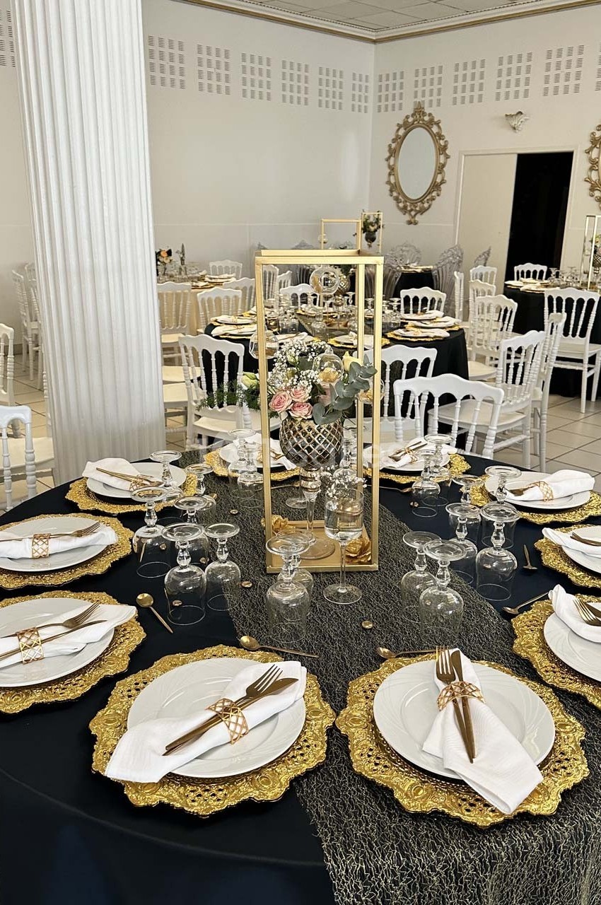Table élégamment dressée avec des assiettes blanches, des serviettes pliées et des décorations dorées dans une salle de…
