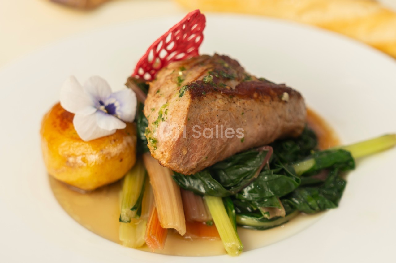 Plat composé d'une pièce de viande grillée, légumes verts, pomme de terre garnie d'une fleur comestible.