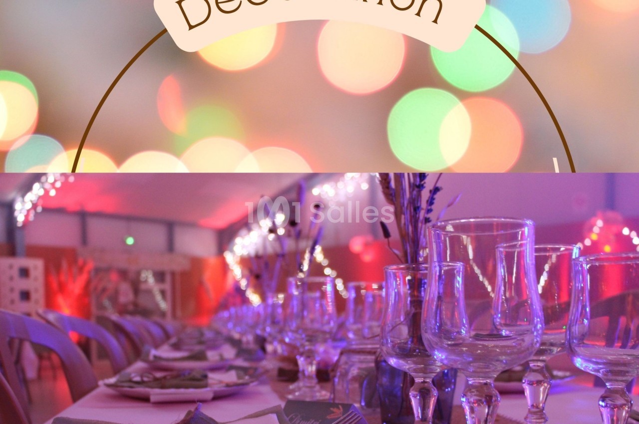 Table décorée avec des verres, serviettes et ornements, éclairée par des lumières colorées en arrière-plan flou.