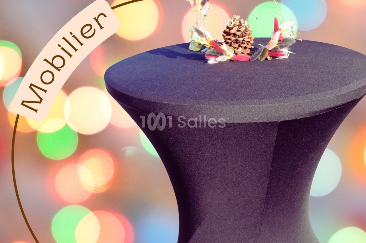 Housse noire ajustée sur une table haute, décorée d'un centre de table avec pomme de pin et feuillage coloré.