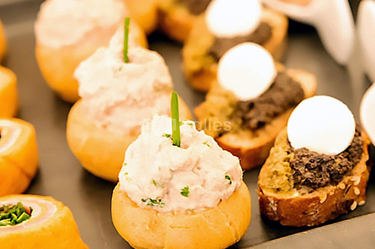 Assortiment de bouchées apéritives avec pain garni de rillettes, tapenade et œufs de caille.