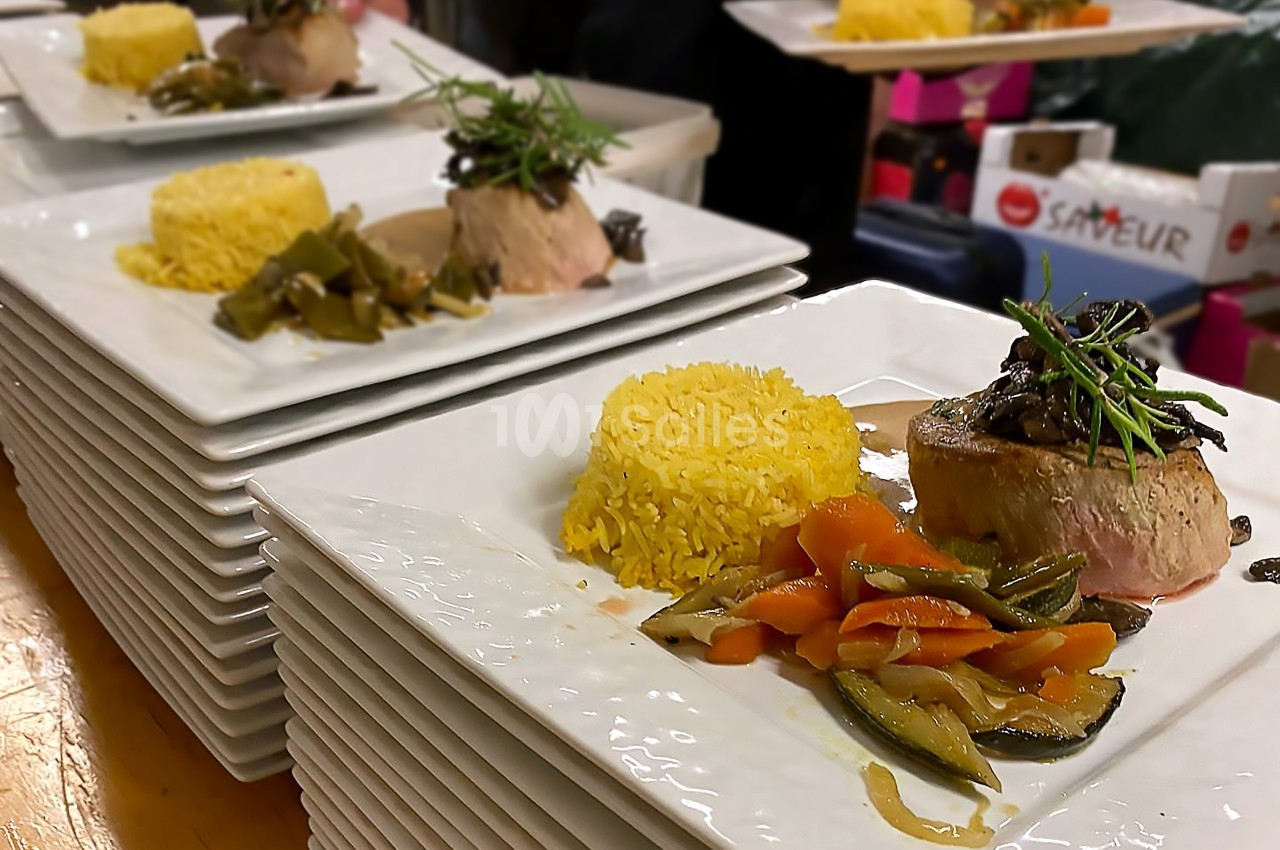 Assiettes dressées avec filet de viande, légumes sautés, riz jaune et garniture de romarin, prêtes à être servies.