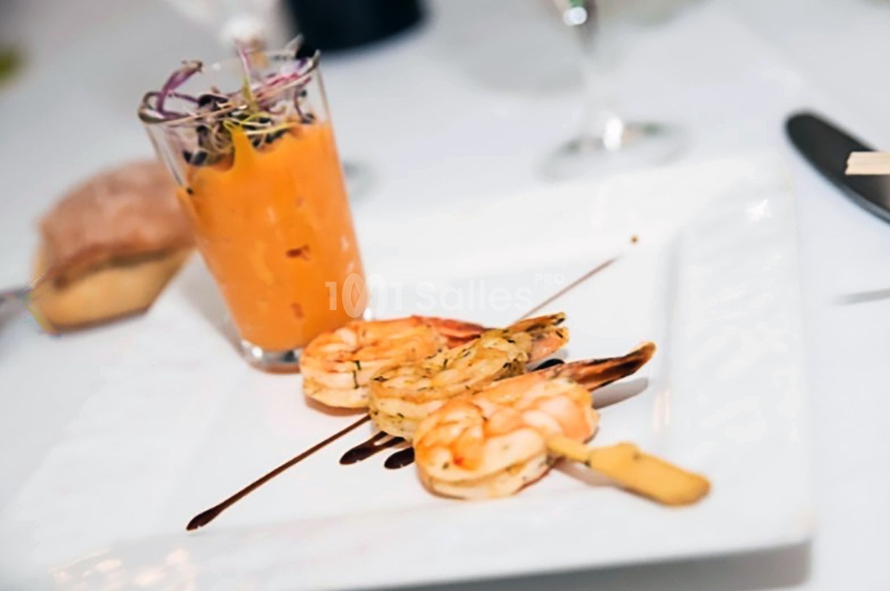 Brochette de crevettes grillées avec filet de sauce balsamique, accompagnée d'un verre de velouté orange.