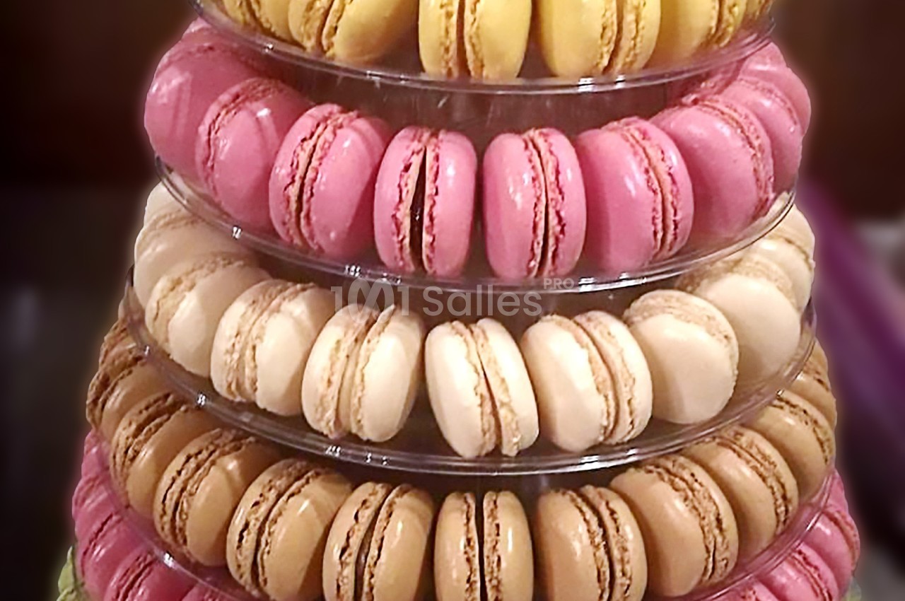 Tour de macarons colorés disposés sur plusieurs étages en plastique transparent.