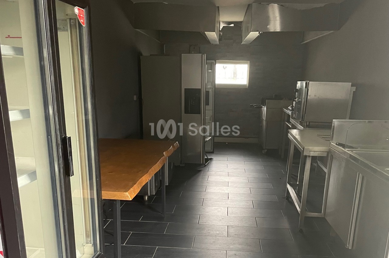 Cuisine professionnelle vide avec équipements en acier inoxydable, réfrigérateur Coca-Cola et plan de travail en bois.
