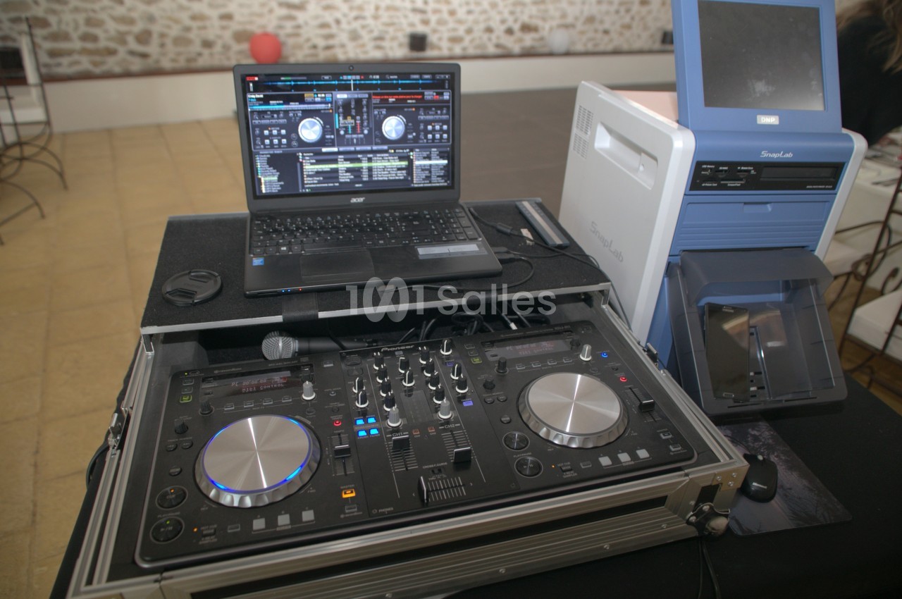 Table de mixage DJ avec ordinateur portable affichant un logiciel de mixage, installée sur une table dans un espace…