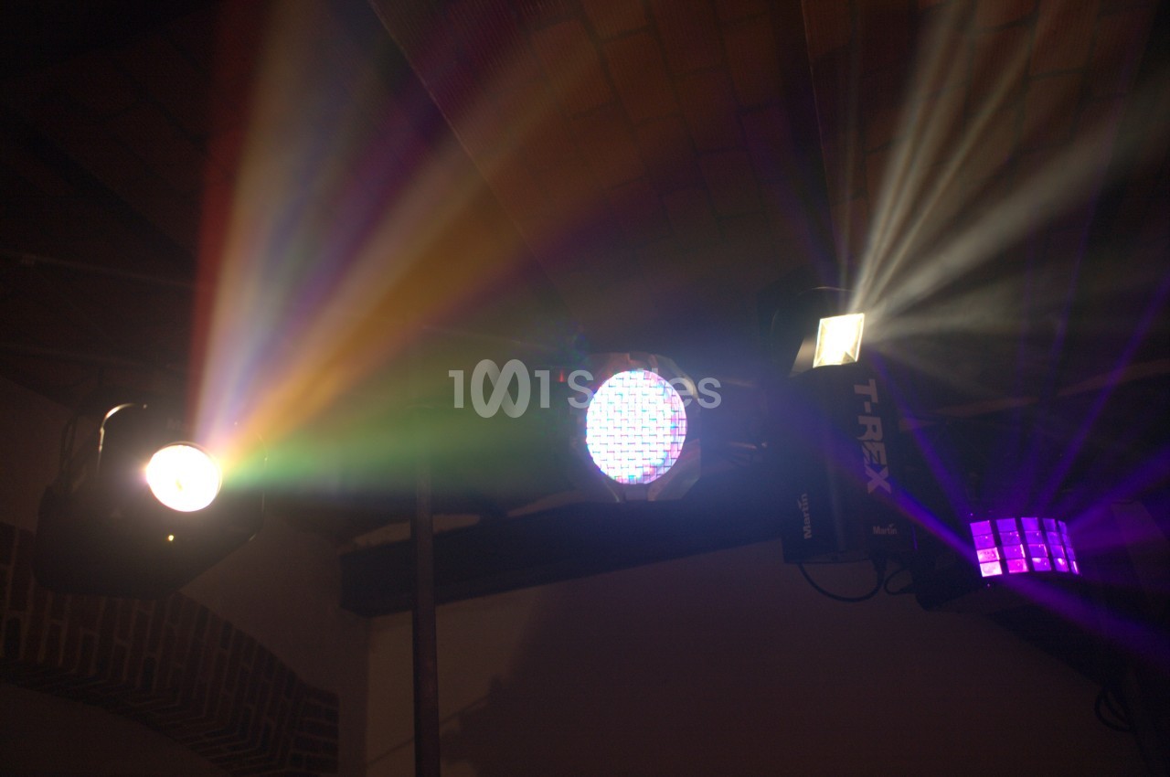 Projecteurs lumineux diffusant des faisceaux colorés dans une pièce sombre avec un plafond en briques.