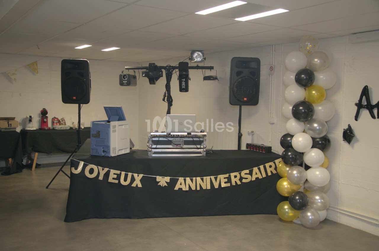 Table de DJ décorée pour un anniversaire, avec guirlande ’Joyeux Anniversaire’, ballons et matériel audio.