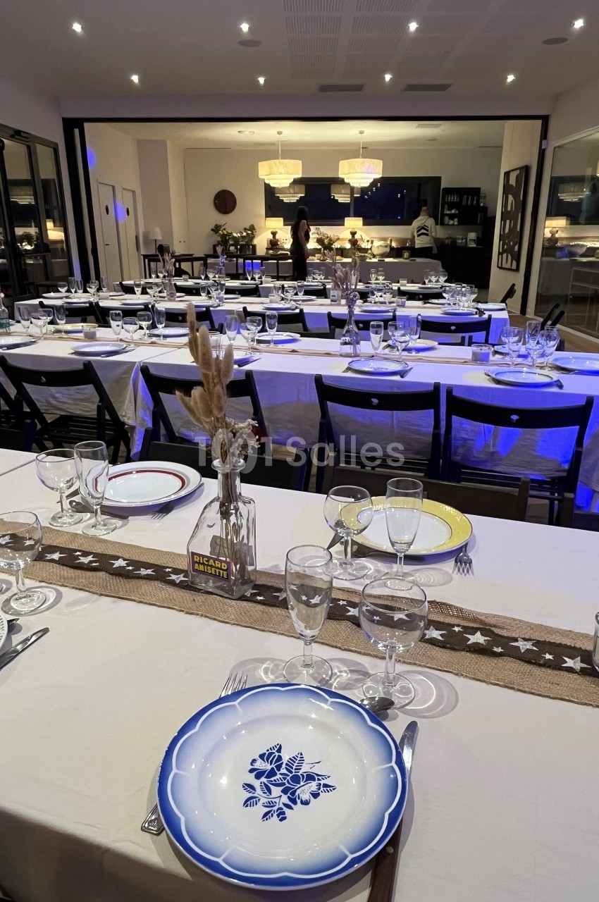 Salle de réception décorée avec des tables dressées, assiettes colorées et ambiance lumineuse chaleureuse.