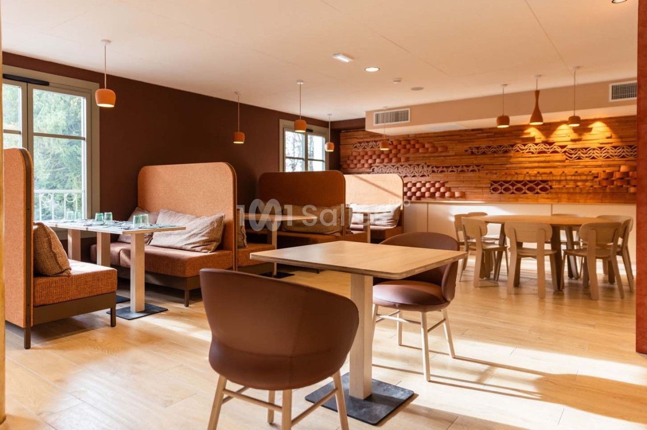 Salle de restaurant lumineuse avec tables en bois, banquettes rembourrées et décor mural en bois.