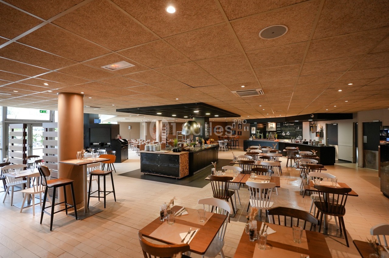 Salle de restaurant lumineuse avec tables en bois, chaises assorties et buffet central moderne.