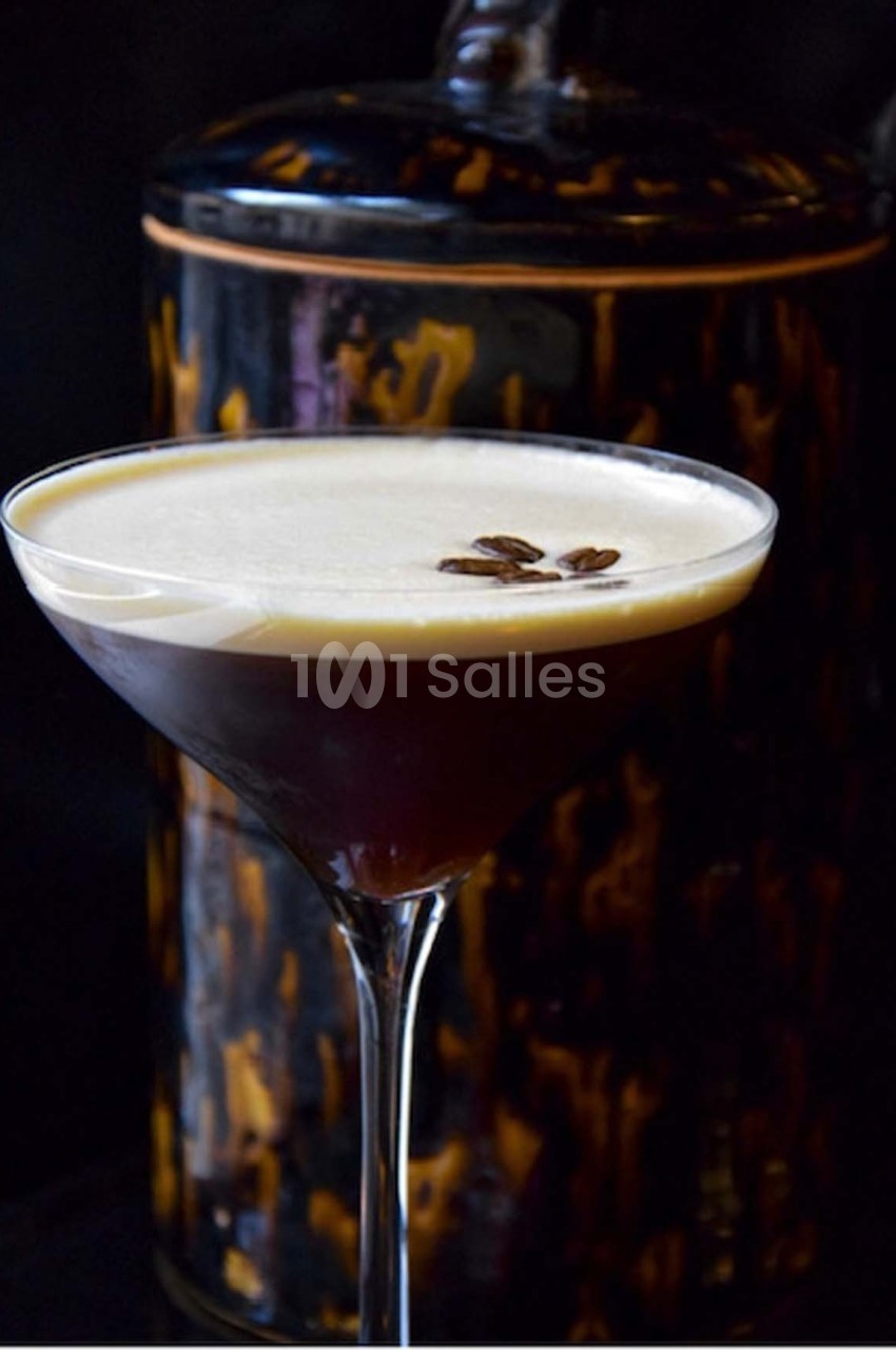 Verre à cocktail rempli d'un espresso martini, garni de grains de café, avec un fond sombre et texturé.