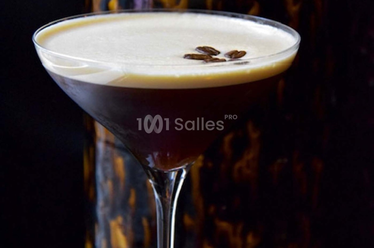 Verre à cocktail rempli d'un espresso martini, surmonté d'une mousse crémeuse et décoré de grains de café.