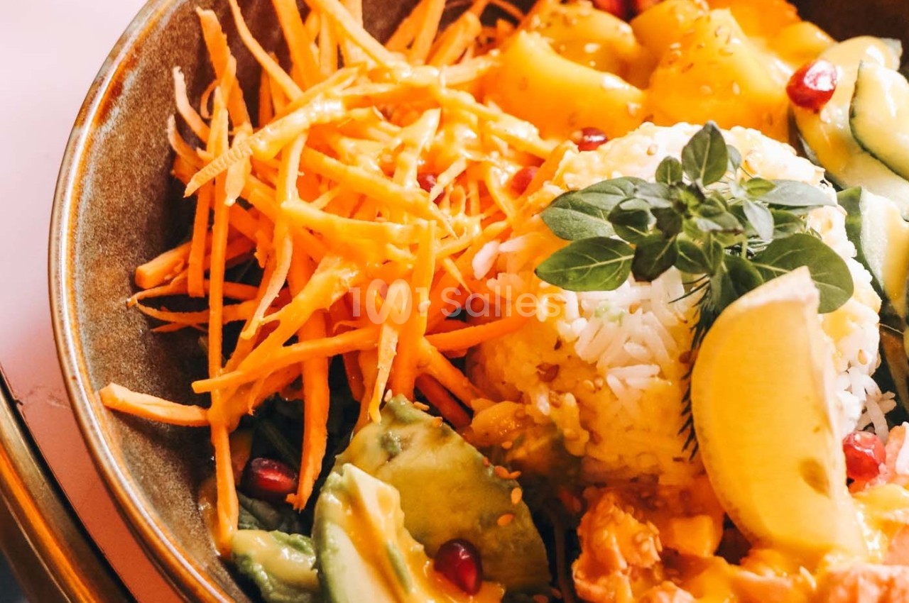 Bol coloré avec riz, carottes râpées, avocat, grenade, citron et herbes fraîches.