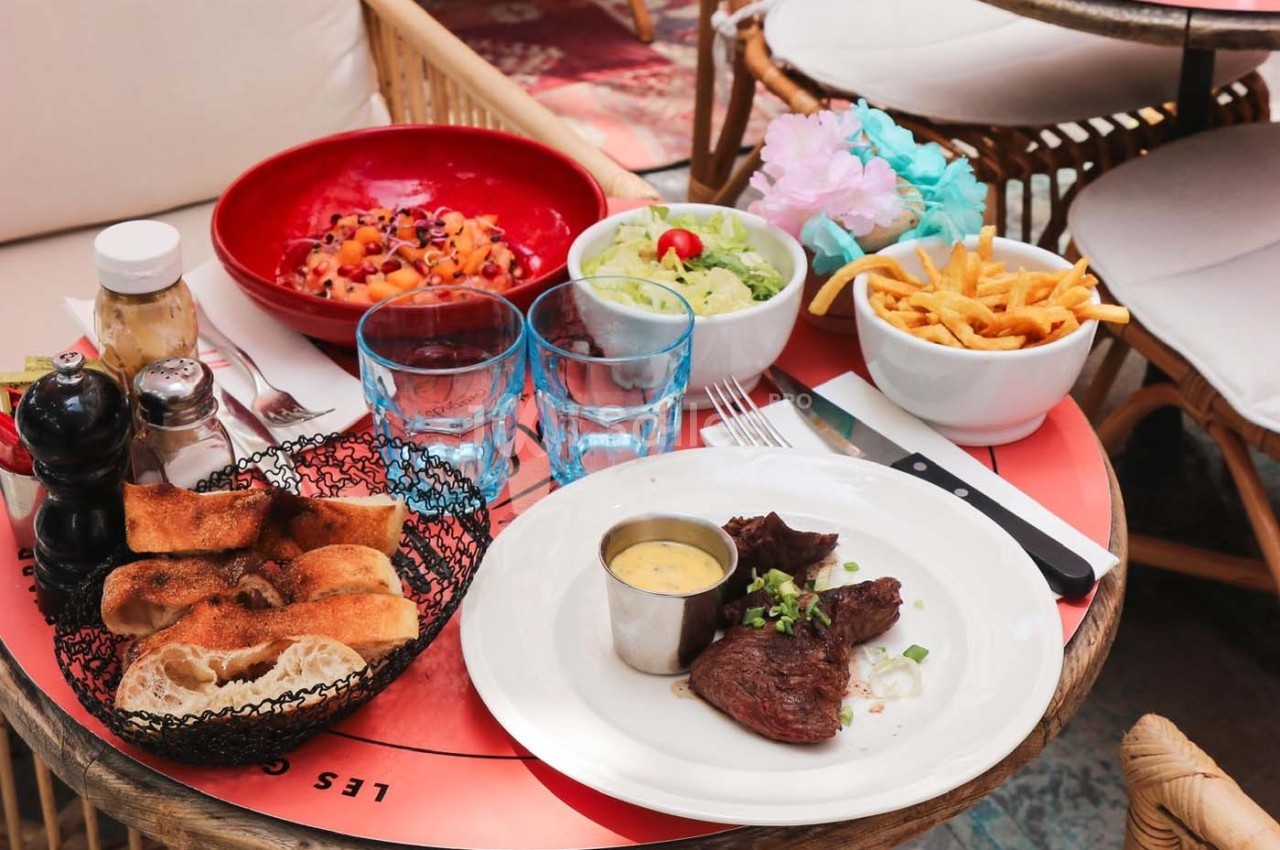 Assiette de viande avec sauce, accompagnée de frites, salade, pain et dessert, servie sur une table de restaurant.