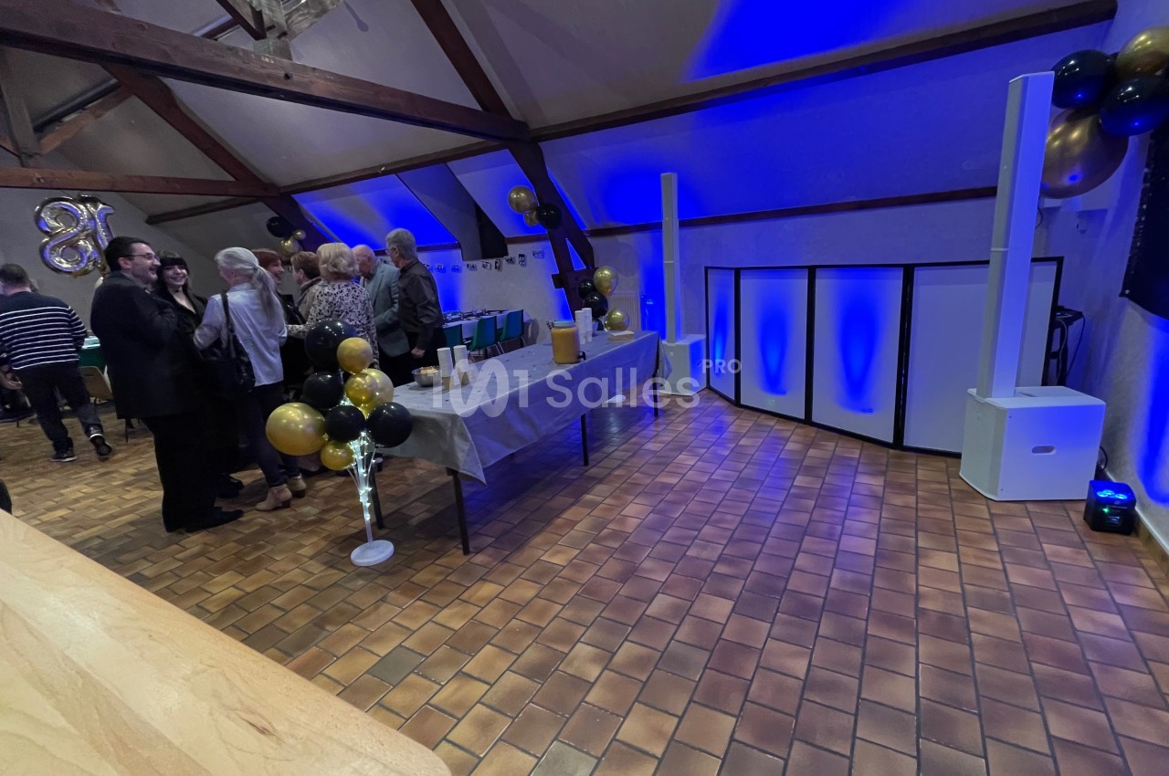 Salle décorée pour un événement avec ballons dorés et noirs, table dressée et éclairage bleu.