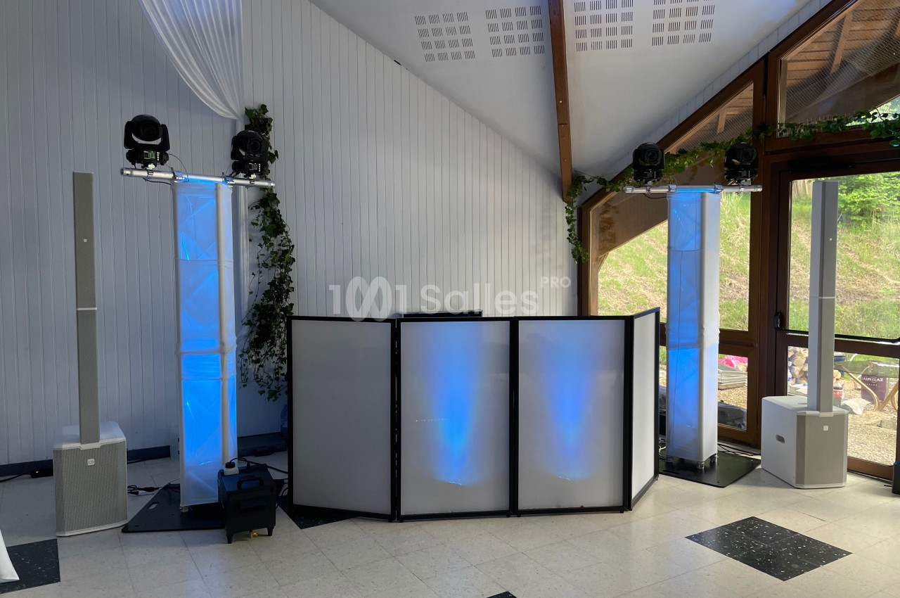 Installation de matériel de sonorisation et éclairage avec des colonnes lumineuses dans une salle aux grandes baies vitrées.