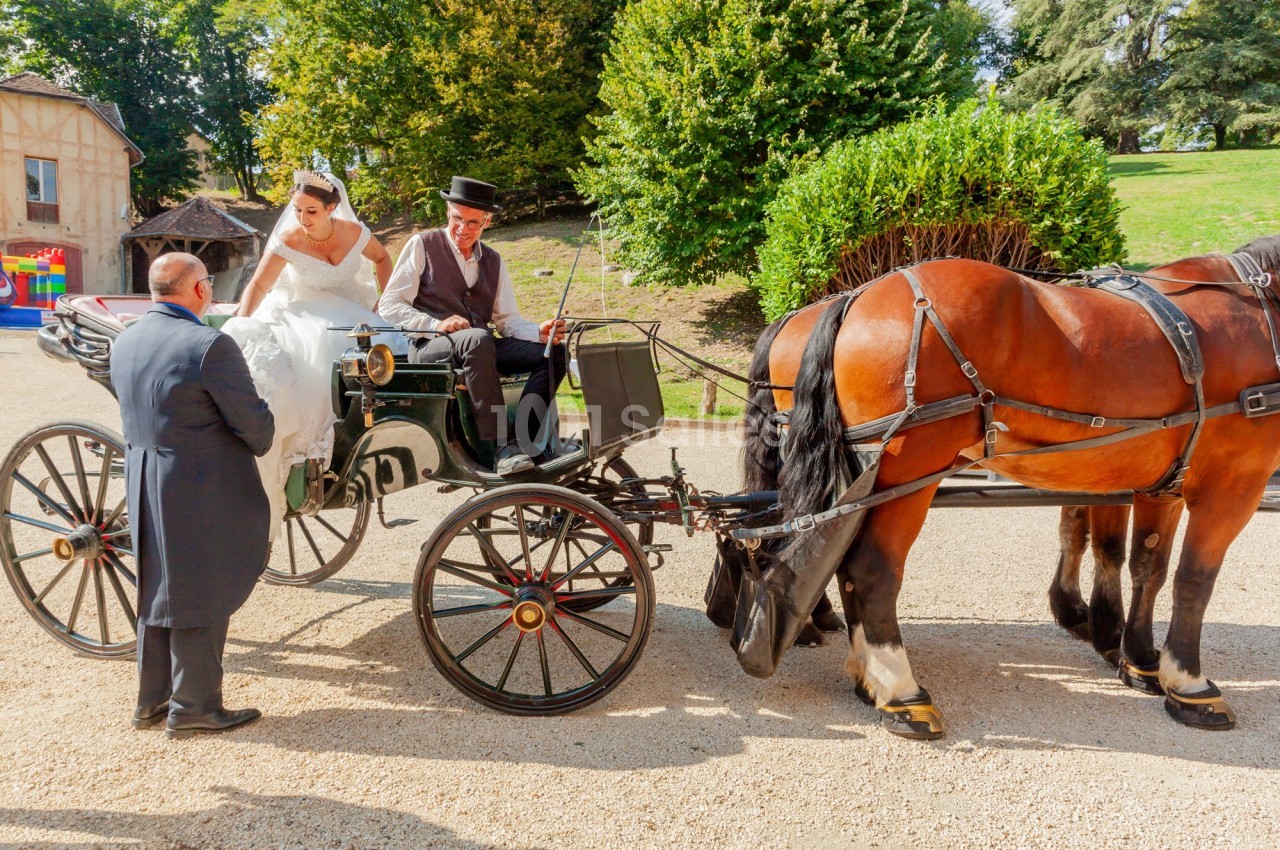 Une mariée monte dans une calèche tirée par deux chevaux, accompagnée d'un cocher et d'un homme en costume.