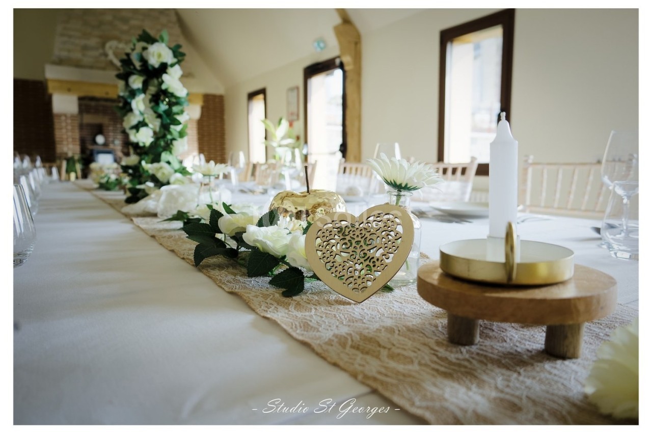 Décoration de table de mariage avec chemin de table en dentelle, fleurs blanches, bougies et ornements dorés en forme de…