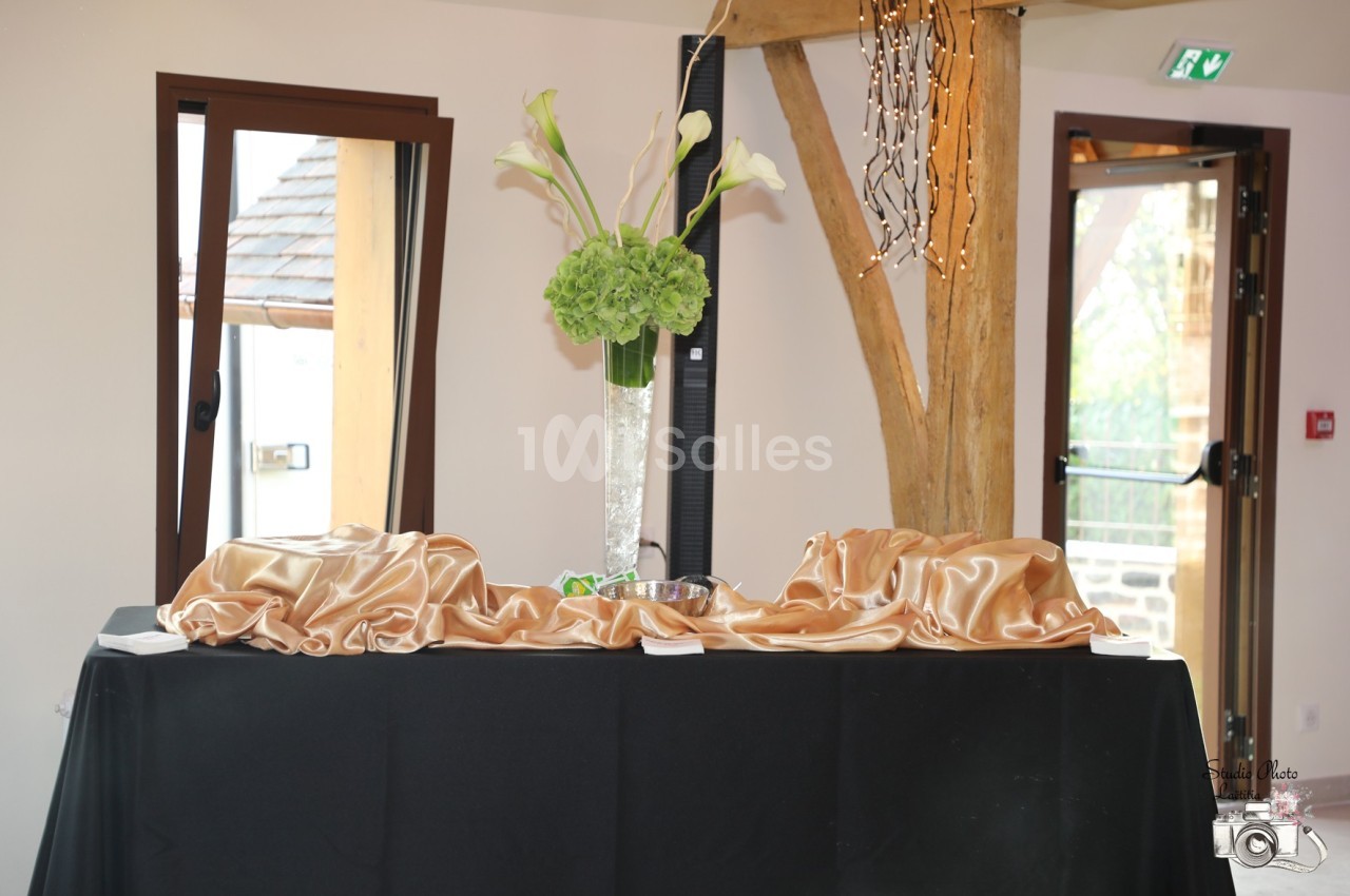 Vase avec des fleurs blanches et vertes sur une table décorée de tissu doré dans une salle lumineuse.