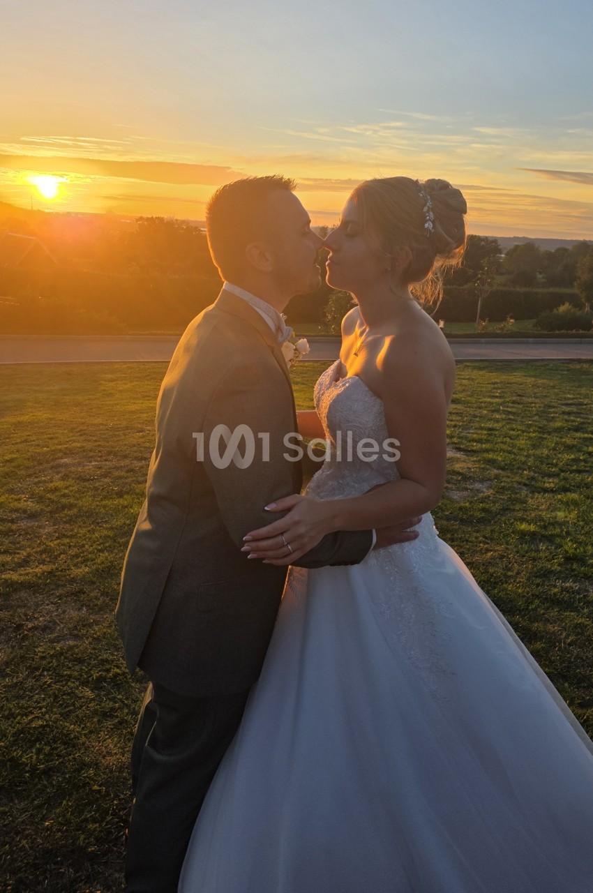 Couple de mariés au coucher de soleil dans un jardin en bord de rivière.