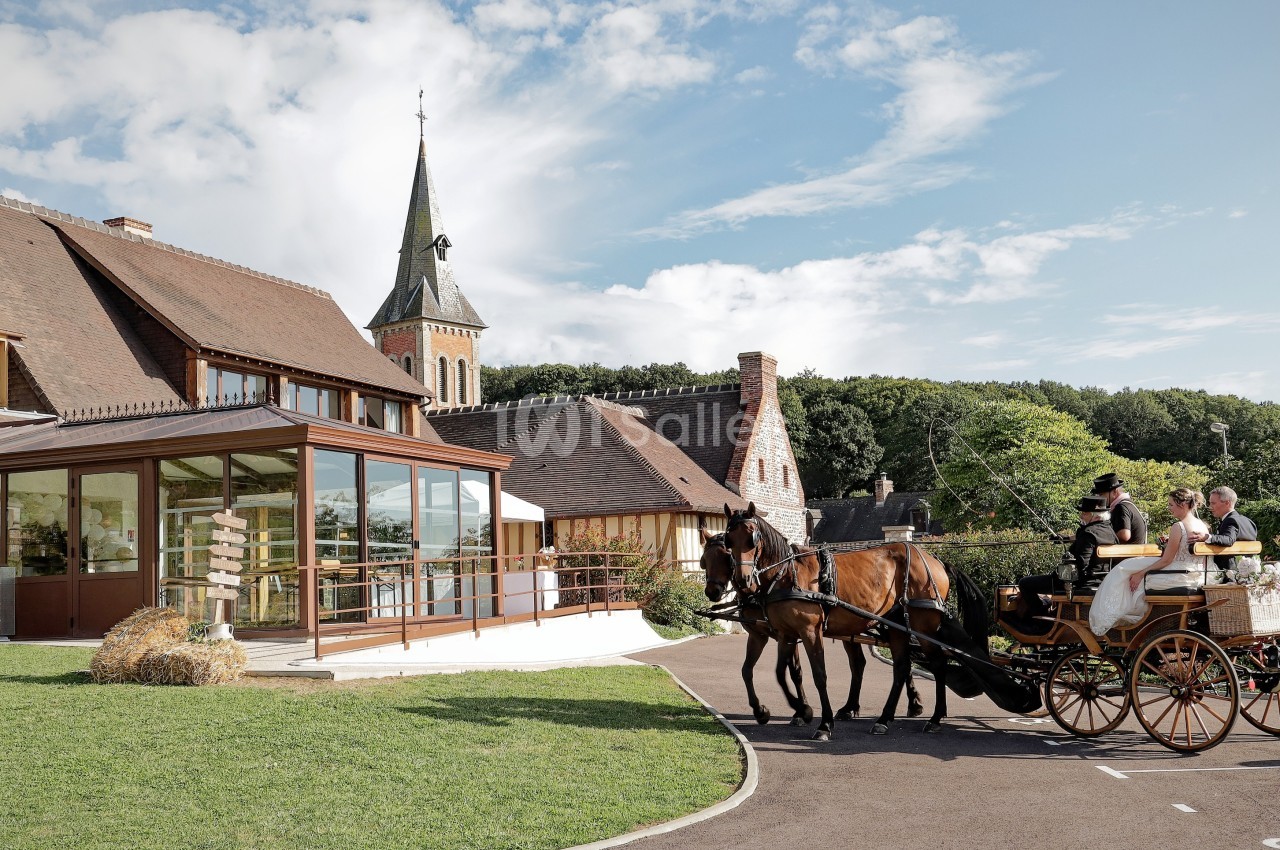 Calèche attelée devant une véranda moderne, manoir normand et église au fond, parc verdoyant.