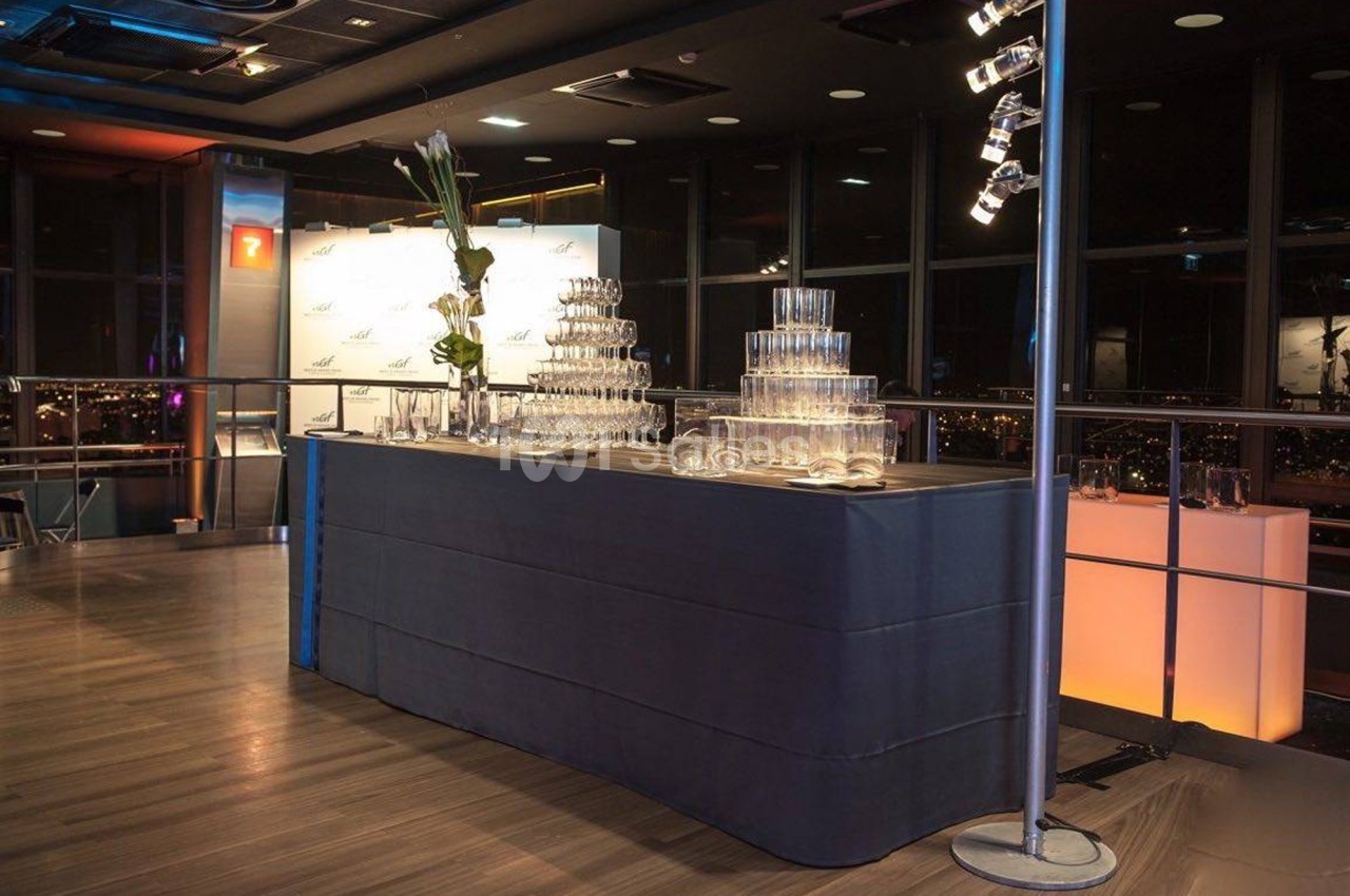 Table de réception avec une pyramide de verres, éclairage tamisé et vue nocturne à travers des baies vitrées.
