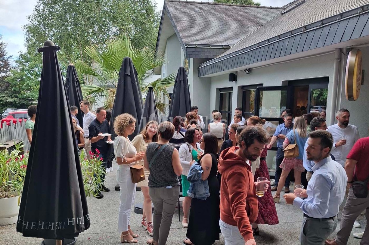 Groupe de personnes discutant et partageant un moment convivial sur une terrasse extérieure près d'un bâtiment.