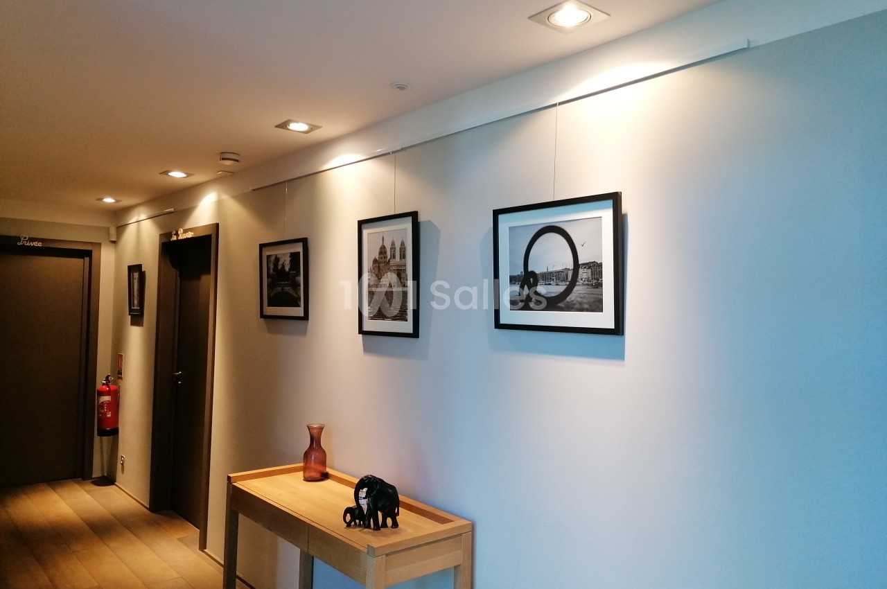 Couloir décoré avec des cadres photo en noir et blanc accrochés au mur, une table en bois et des objets décoratifs.
