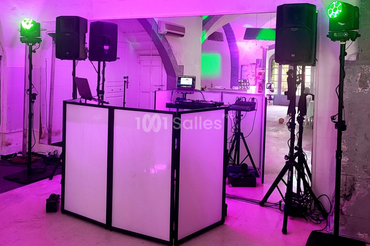 Installation de matériel de sonorisation et d'éclairage avec une table de mixage dans une salle à l'ambiance lumineuse…