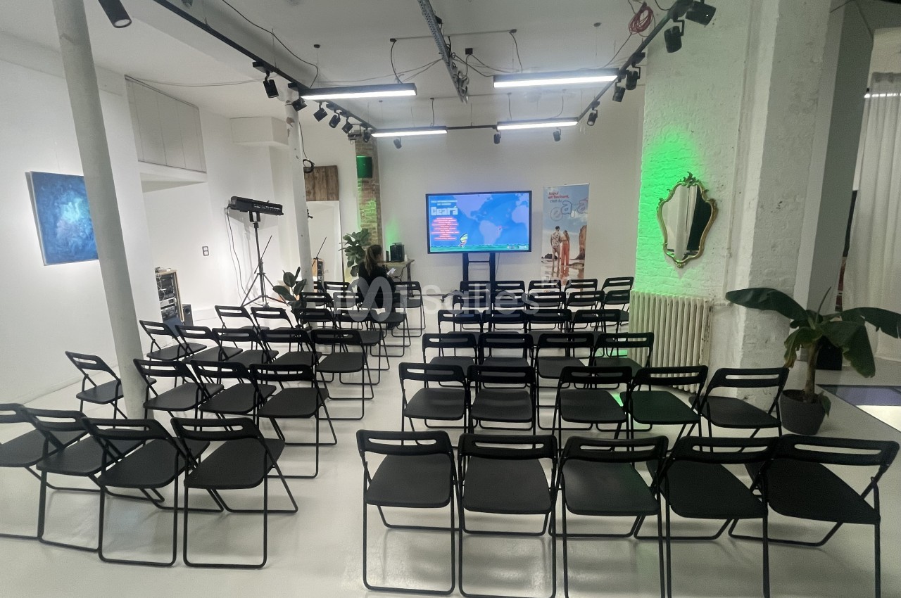 Salle de conférence moderne avec des rangées de chaises noires vides et un écran affichant une carte du monde.