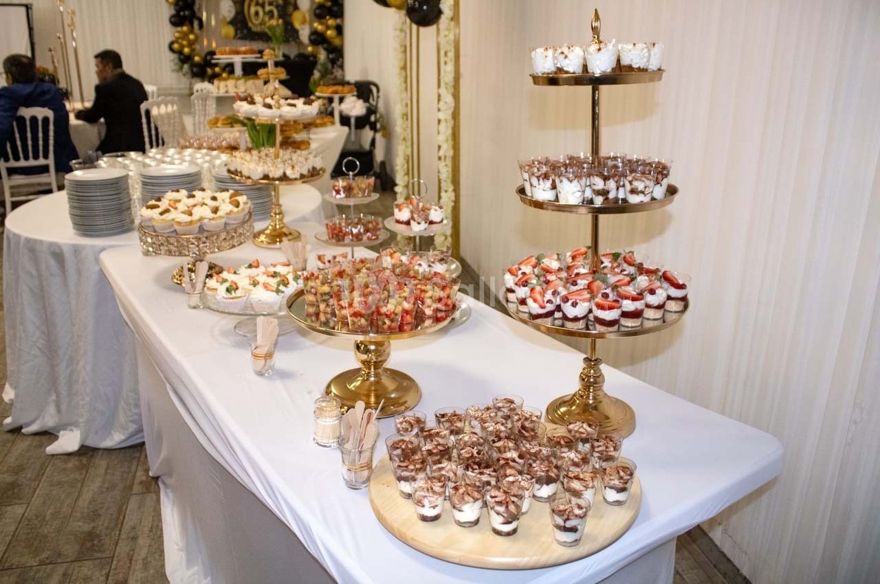 Table dressée avec des desserts variés, dont verrines, gâteaux et pâtisseries, présentés sur des supports dorés.