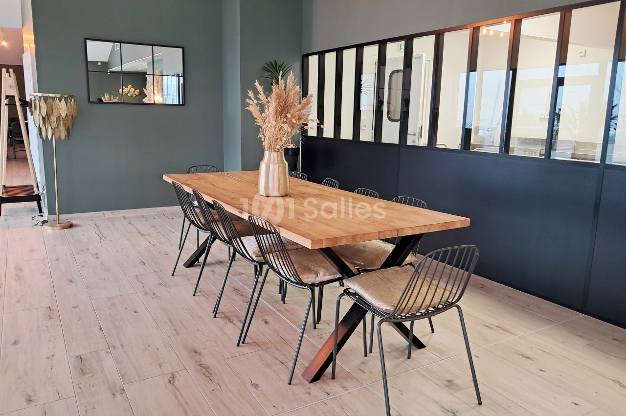 Salle à manger moderne avec table en bois, chaises noires et décoration minimaliste dans un espace lumineux.