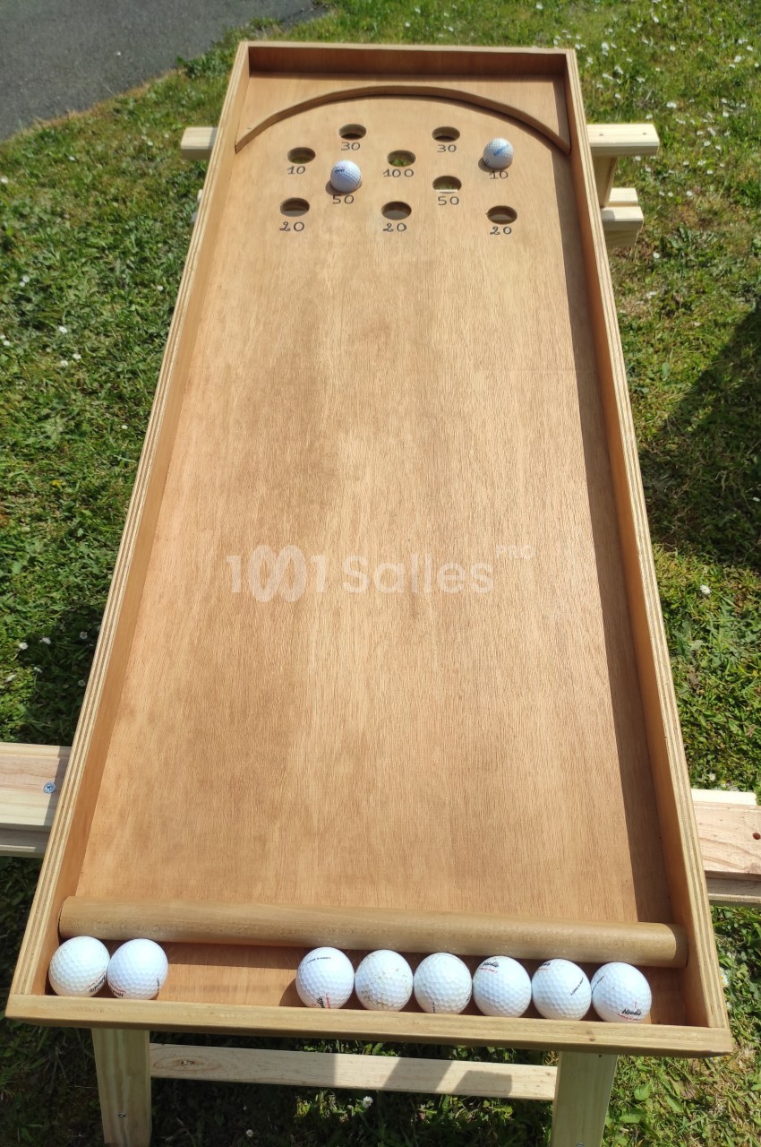 Jeu de billard hollandais en bois avec des boules blanches alignées en bas, posé sur une pelouse.