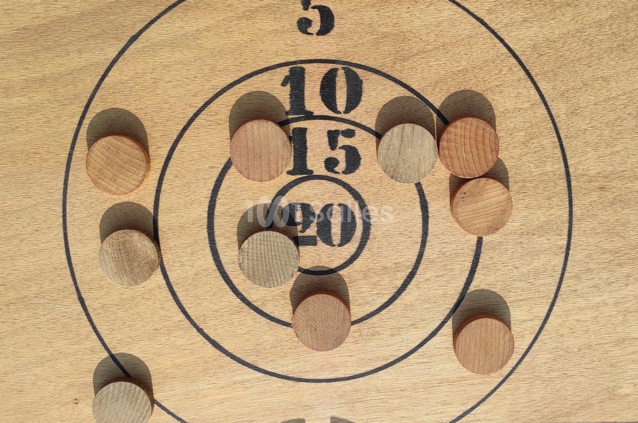 Disque en bois avec des cercles numérotés et des pions en bois disposés sur différentes zones de points.