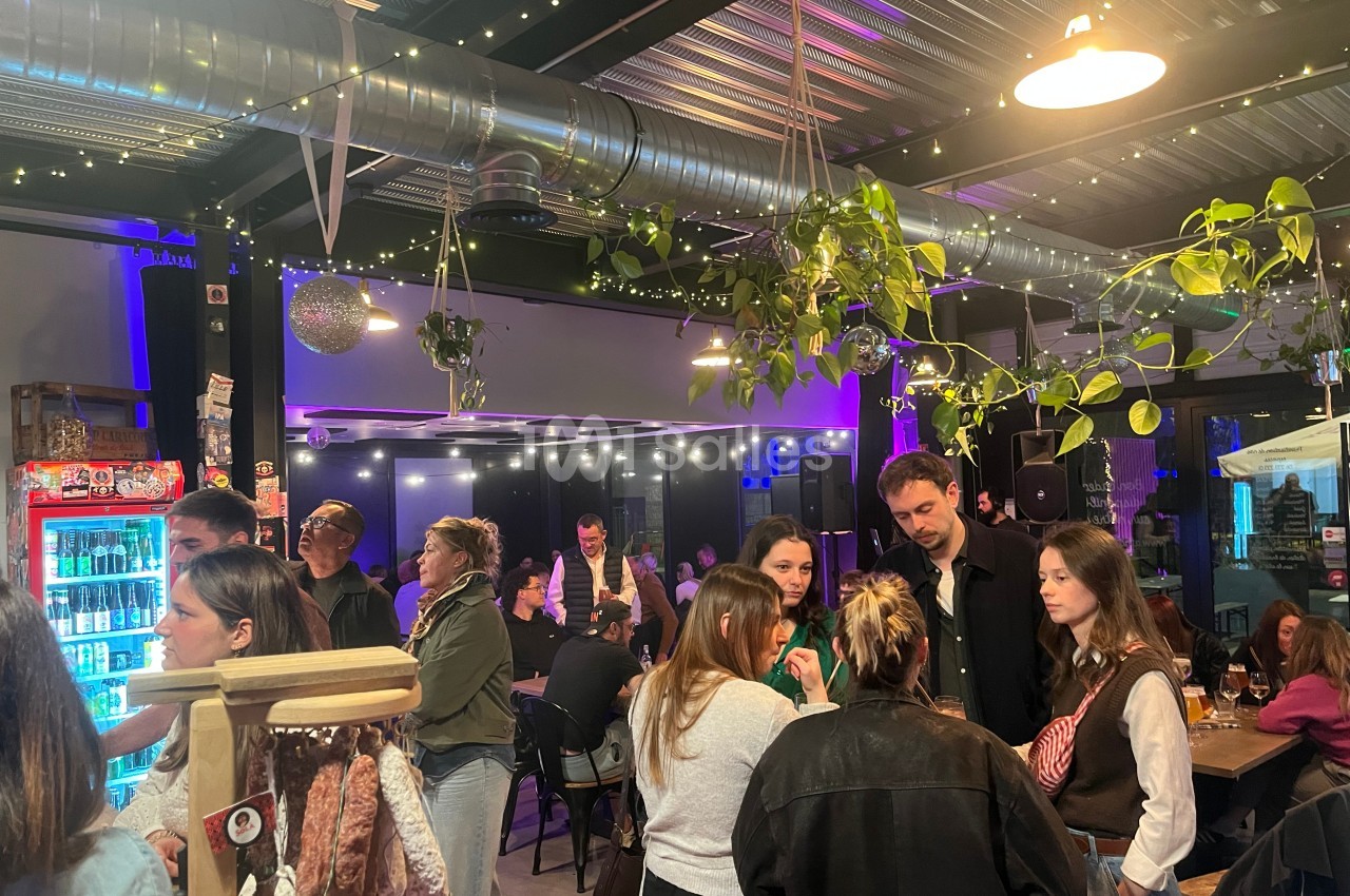 Groupe de personnes discutant et partageant un moment convivial dans un bar décoré de plantes et de lumières.