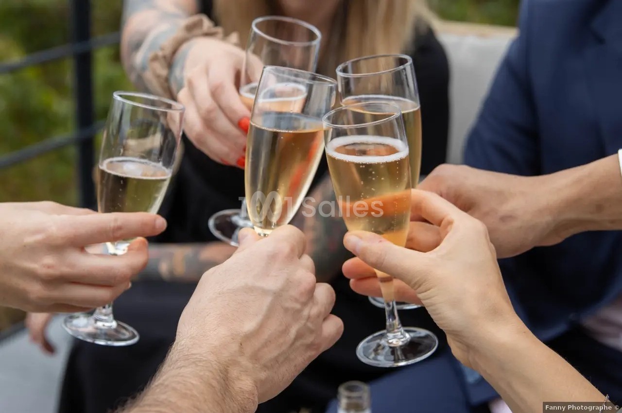 Des mains trinquent avec des flûtes de champagne lors d'une célébration en extérieur.