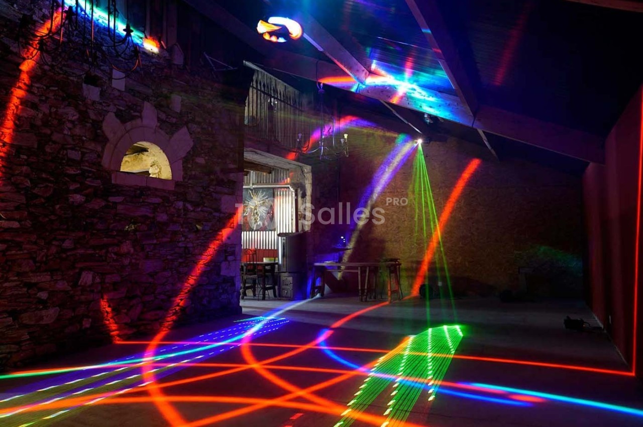 Salle en pierre avec des jeux de lumières colorées projetés sur le sol et les murs, ambiance festive.